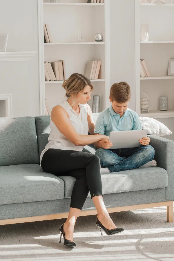 Leena teaching her son Leena sitting on the couch with her son, using a tablet together, reflecting her passion for learning and sharing knowledge.